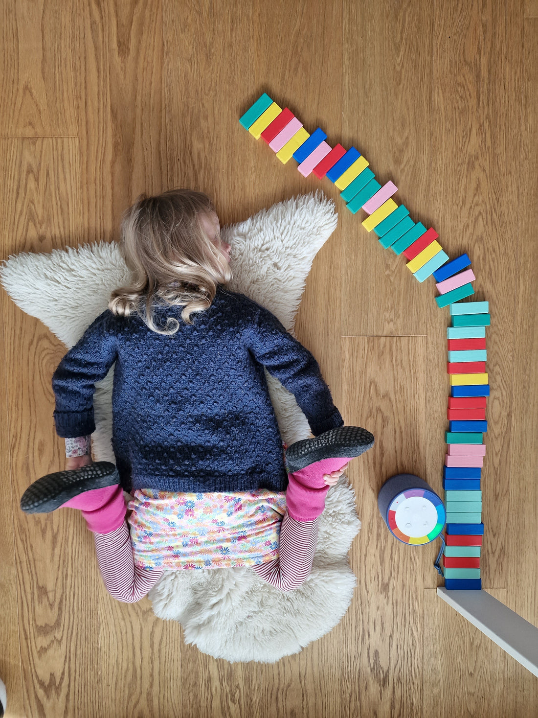 Kind liegt entspannt auf einem Fell und sortiert bunte Steine beim Hören der wobie box – achtsame kreative Ruhezeit für Kinder.